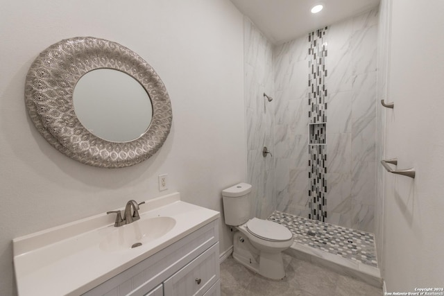 bathroom featuring a tile shower, tile patterned flooring, vanity, and toilet