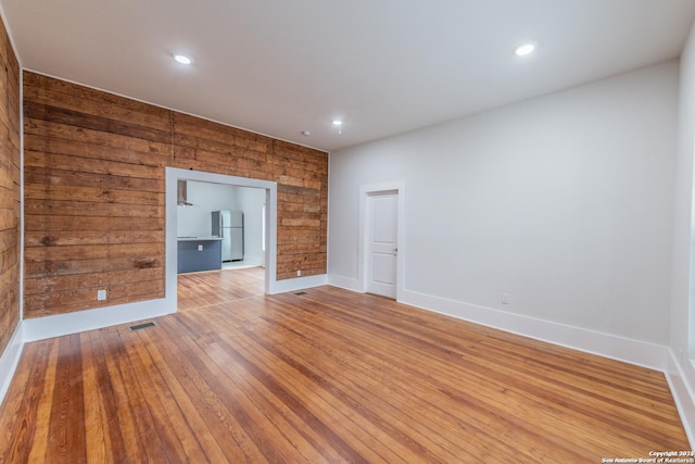 unfurnished living room featuring wooden walls and hardwood / wood-style floors