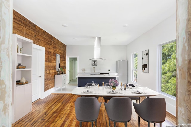 kitchen featuring kitchen peninsula, island range hood, wood-type flooring, white refrigerator, and wood walls