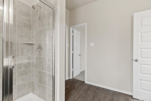 bathroom with a shower with shower door and wood-type flooring