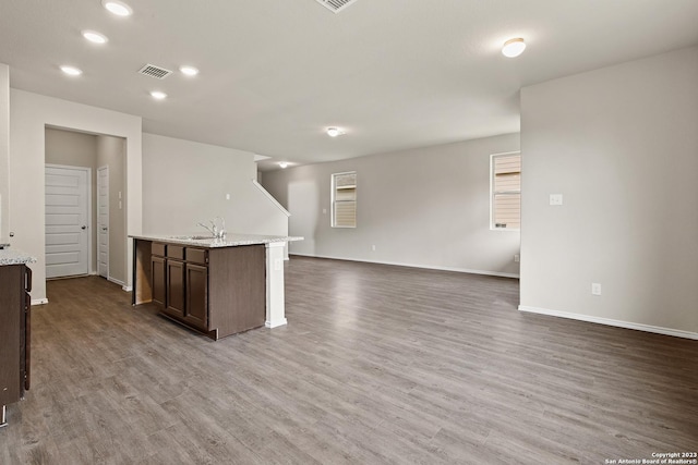 kitchen with dark brown cabinets, an island with sink, wood-type flooring, and sink