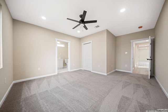 unfurnished bedroom with ensuite bathroom, a closet, ceiling fan, and light colored carpet