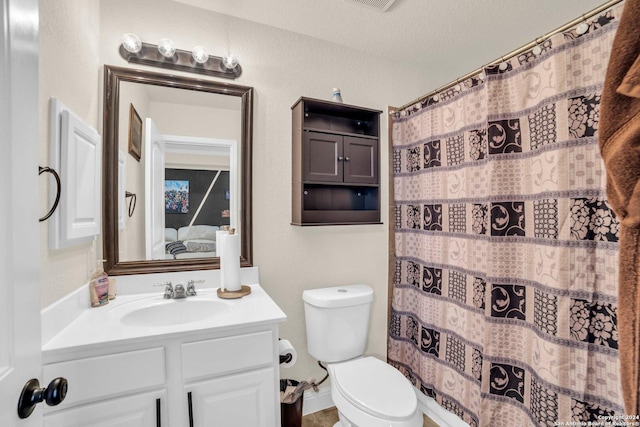 bathroom featuring a textured ceiling, vanity, toilet, and walk in shower