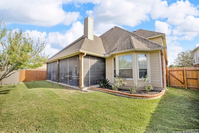 back of property featuring a lawn and a sunroom