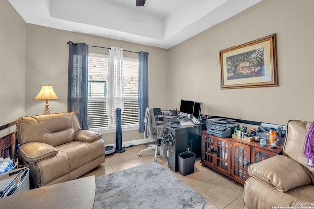 office featuring a tray ceiling, ceiling fan, and light tile patterned floors