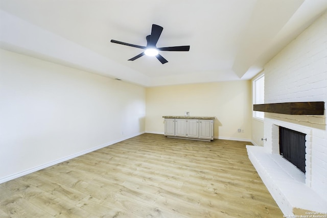 unfurnished living room featuring light hardwood / wood-style flooring, a brick fireplace, and ceiling fan