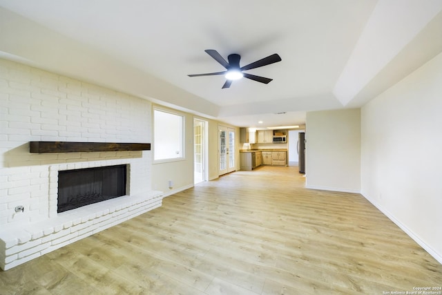 unfurnished living room featuring ceiling fan, light hardwood / wood-style flooring, and a brick fireplace