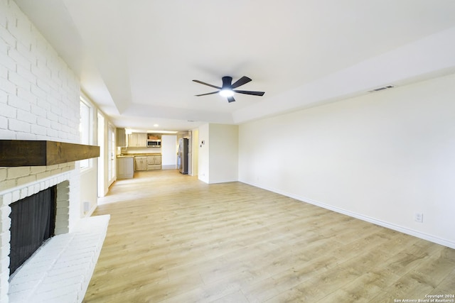 unfurnished living room featuring ceiling fan, light hardwood / wood-style flooring, and a brick fireplace