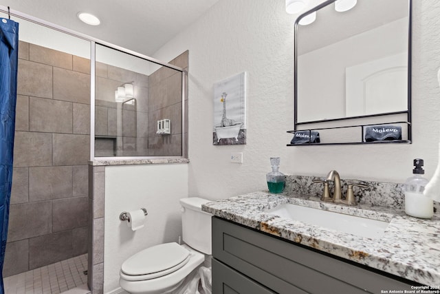 bathroom with vanity, toilet, and tiled shower