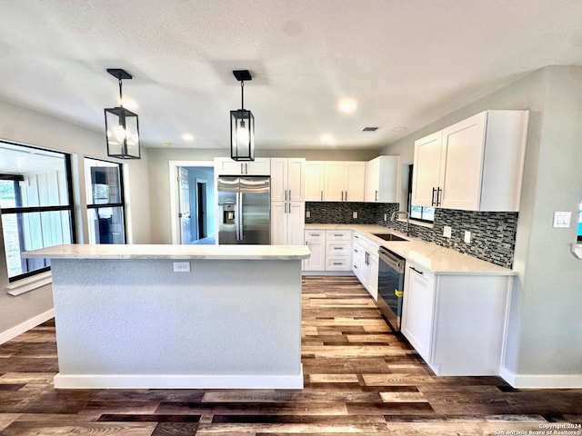 kitchen with stainless steel appliances, a kitchen island, white cabinetry, and sink