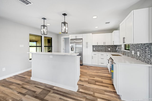 kitchen with a center island, white cabinets, sink, stainless steel fridge, and light wood-type flooring