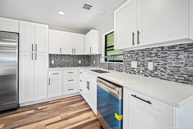 kitchen with hardwood / wood-style floors, sink, appliances with stainless steel finishes, light stone counters, and white cabinetry