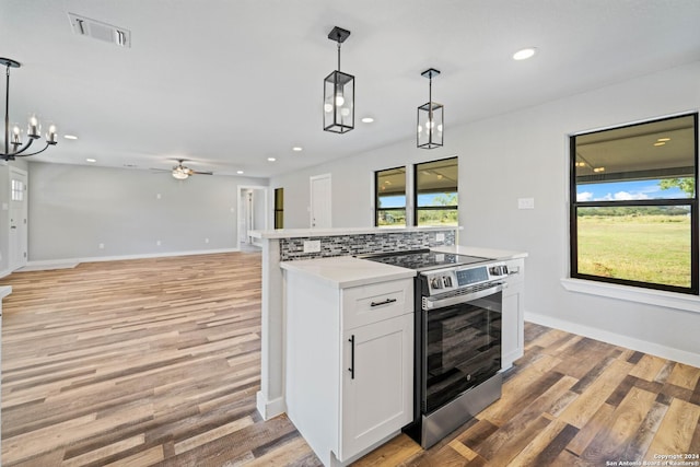 kitchen featuring electric stove, white cabinetry, a healthy amount of sunlight, and decorative light fixtures