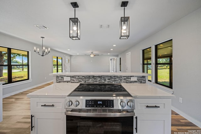 kitchen with high end range, pendant lighting, white cabinets, ceiling fan with notable chandelier, and light wood-type flooring