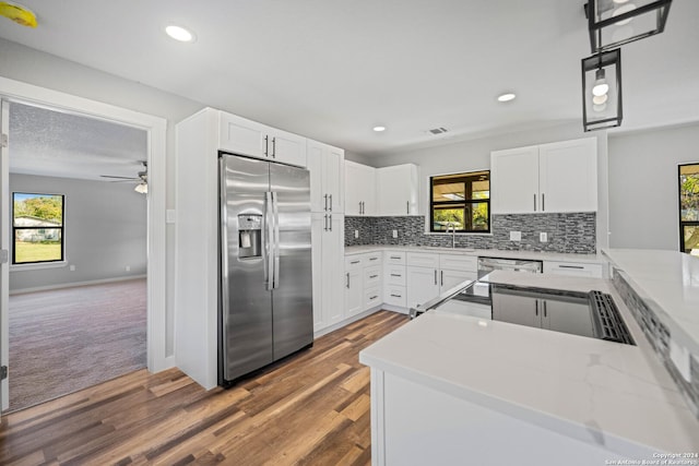 kitchen featuring stainless steel fridge, decorative light fixtures, white cabinetry, and a healthy amount of sunlight