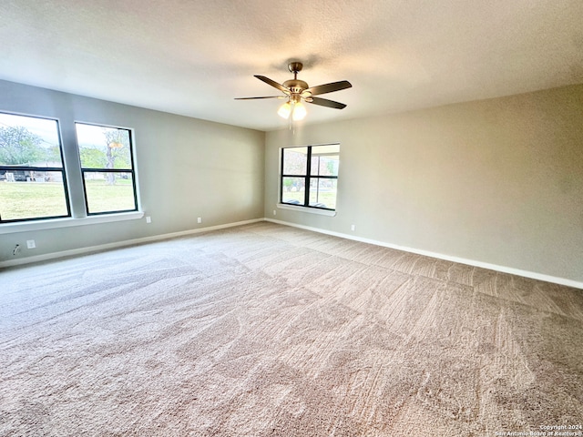 carpeted spare room featuring ceiling fan, a textured ceiling, and a wealth of natural light