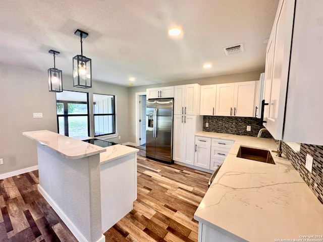 kitchen featuring stainless steel fridge, sink, decorative light fixtures, light hardwood / wood-style flooring, and white cabinetry