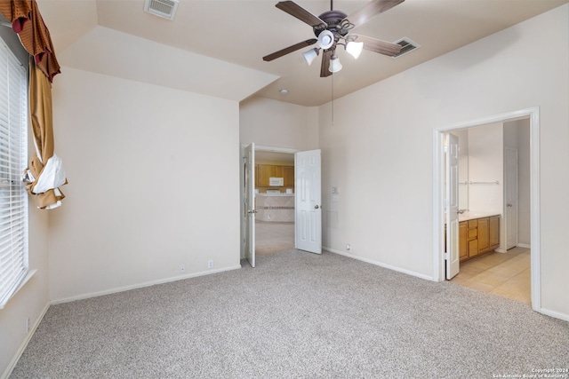 unfurnished bedroom with light carpet, connected bathroom, and ceiling fan