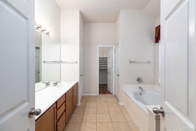 bathroom featuring tile patterned flooring, vanity, and tiled tub