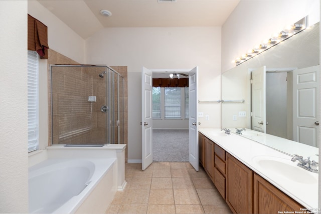 bathroom with tile patterned flooring, vanity, separate shower and tub, and vaulted ceiling