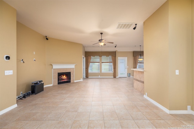 unfurnished living room with a tiled fireplace, ceiling fan, and light tile patterned floors