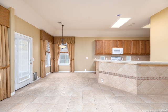 kitchen with decorative light fixtures, white appliances, kitchen peninsula, and a wealth of natural light