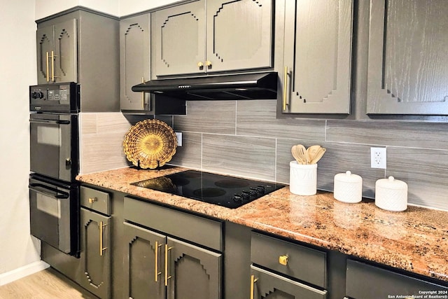 kitchen featuring backsplash, light stone countertops, and black appliances