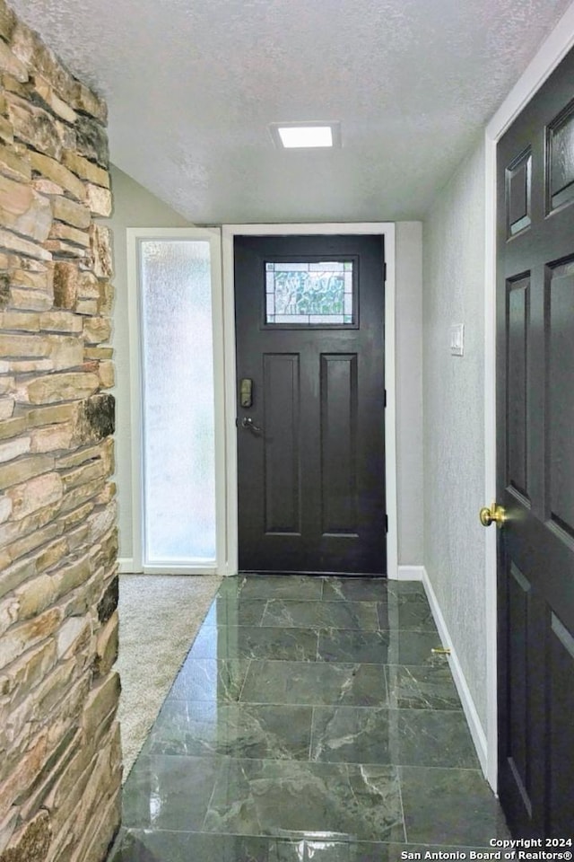 foyer with a textured ceiling and vaulted ceiling