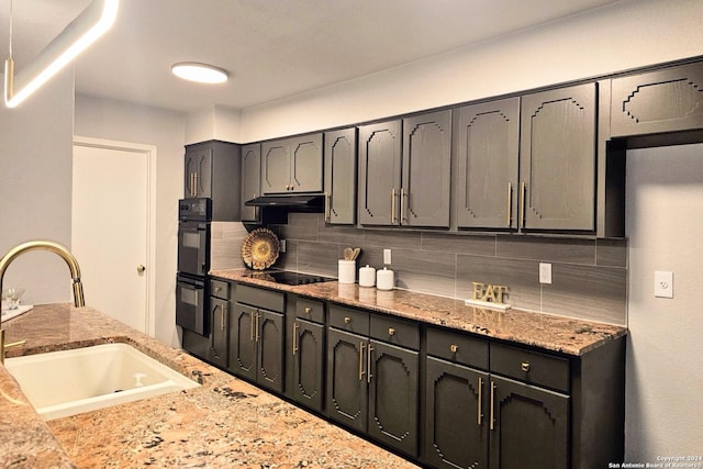 kitchen featuring decorative backsplash, light stone countertops, sink, and black appliances