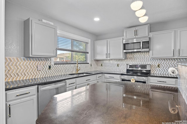 kitchen with decorative backsplash, appliances with stainless steel finishes, dark stone countertops, and sink