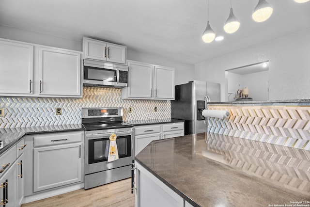 kitchen featuring decorative backsplash, light hardwood / wood-style flooring, hanging light fixtures, and appliances with stainless steel finishes