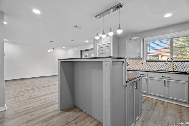 kitchen featuring pendant lighting, a center island, gray cabinets, and sink