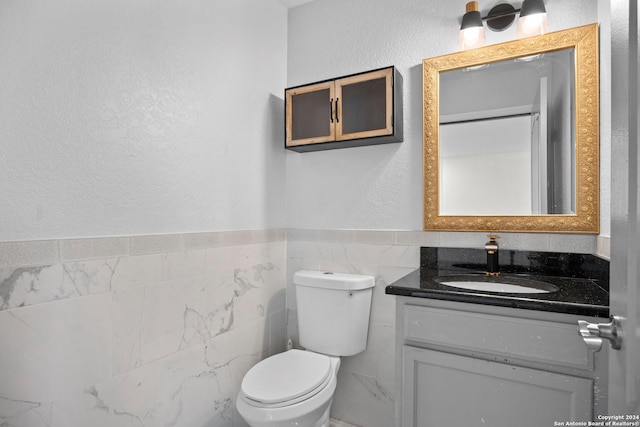 bathroom with vanity, tile walls, and toilet