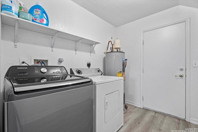 washroom featuring independent washer and dryer, a textured ceiling, light hardwood / wood-style floors, and water heater