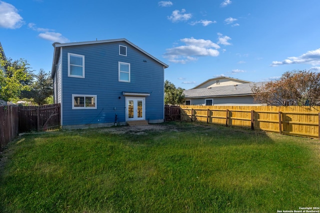 rear view of property featuring french doors and a lawn