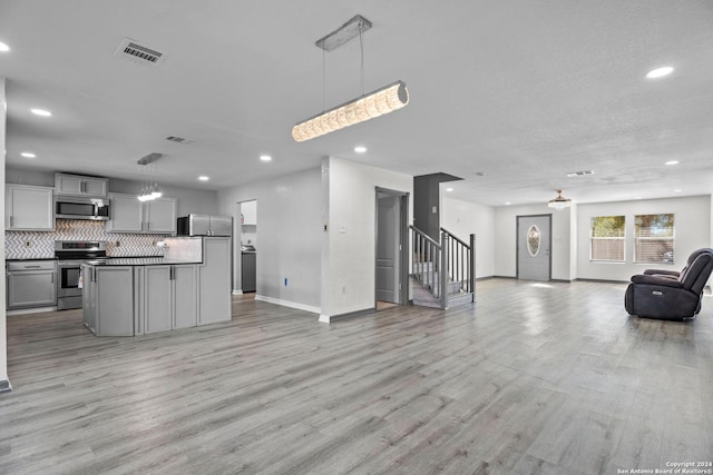 kitchen featuring appliances with stainless steel finishes, light wood-type flooring, gray cabinets, and decorative light fixtures