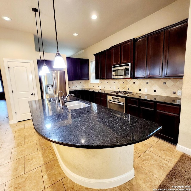 kitchen with sink, dark stone counters, pendant lighting, a center island with sink, and appliances with stainless steel finishes