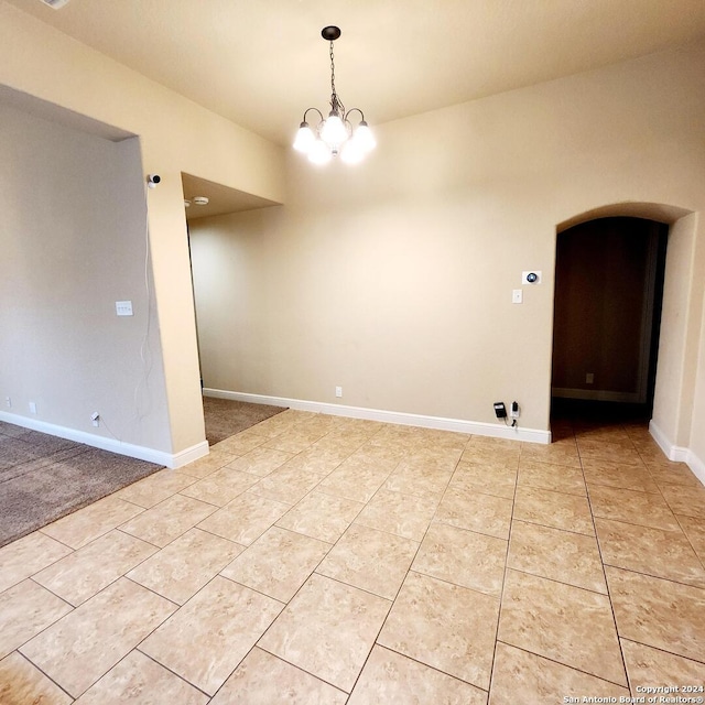 carpeted spare room with an inviting chandelier