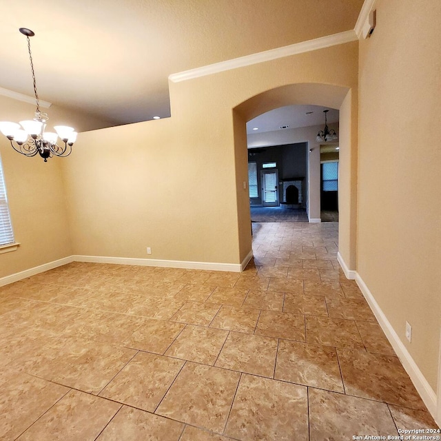 spare room featuring ornamental molding and a notable chandelier