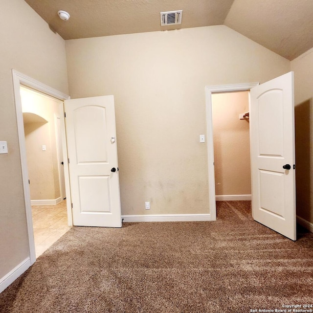 carpeted spare room with vaulted ceiling