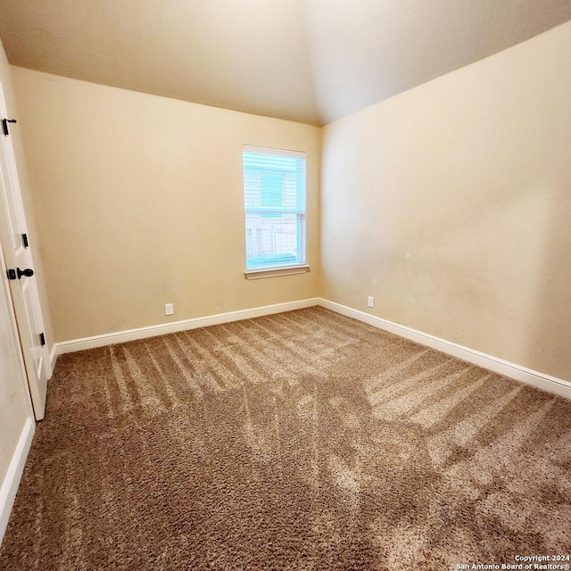 carpeted spare room featuring vaulted ceiling