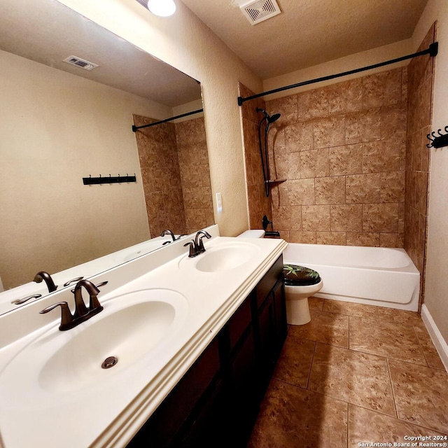 full bathroom featuring vanity, tiled shower / bath combo, a textured ceiling, and toilet