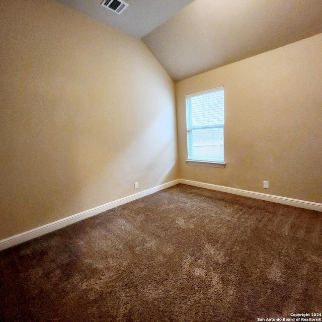 spare room with carpet flooring and lofted ceiling