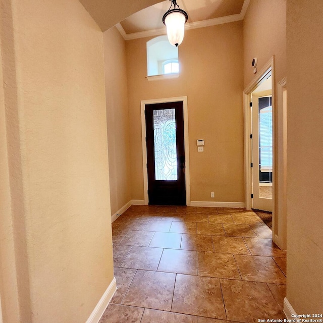 foyer entrance featuring light tile patterned floors, a high ceiling, and ornamental molding