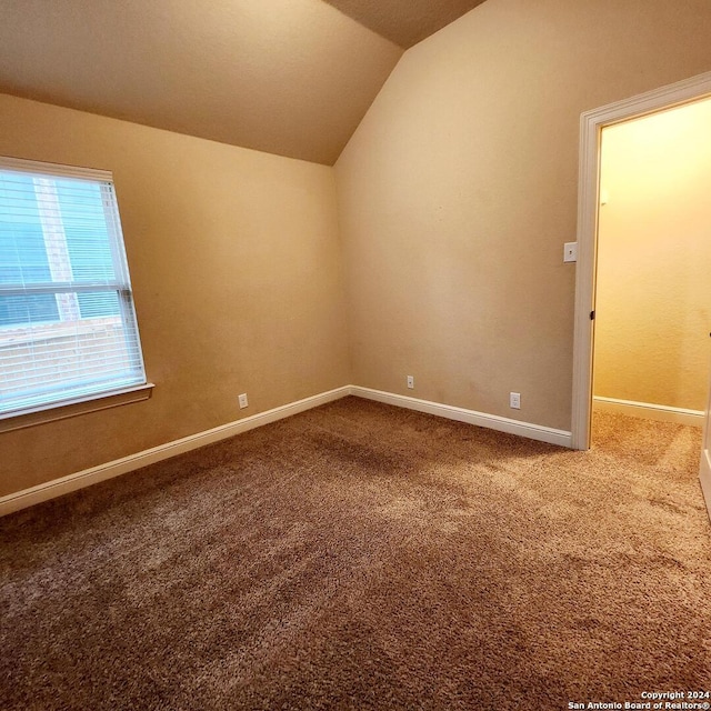 carpeted spare room with lofted ceiling