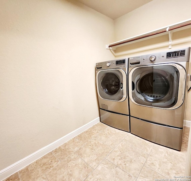 clothes washing area featuring washer and clothes dryer and light tile patterned flooring