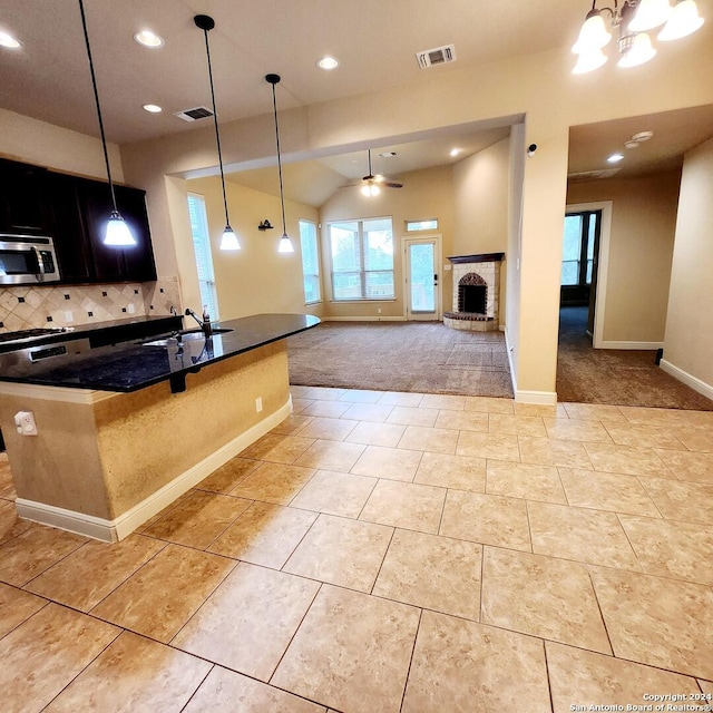 kitchen with pendant lighting, ceiling fan with notable chandelier, sink, a fireplace, and light colored carpet