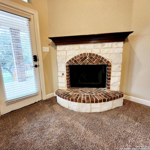 interior details featuring a stone fireplace and carpet floors