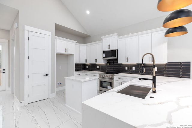 kitchen featuring appliances with stainless steel finishes, light stone counters, a kitchen island, sink, and white cabinetry