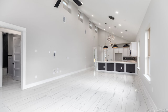 unfurnished living room featuring ceiling fan, sink, and high vaulted ceiling